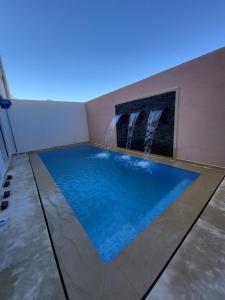 a swimming pool with a water fountain in a room at Villa Sereine in Sidi Yahia