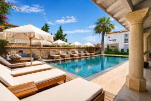 an outdoor swimming pool with lounge chairs and umbrellas at Alaçatı Limonaia Hotel in Alaçatı
