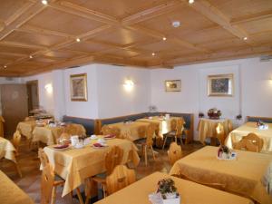 una sala da pranzo con tavoli, sedie e soffitto di Residence Garni Manuela a Cavalese