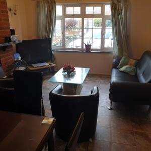 a living room with a table and chairs and a couch at Heathrow Ensuite in West Drayton +1 photo
