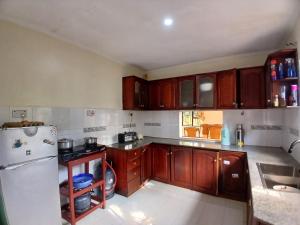 a kitchen with wooden cabinets and a white refrigerator at Friendly hostel in Arusha