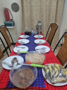 a table with a red table cloth with food on it at Friendly hostel in Arusha