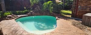 a small swimming pool in a yard with a stone wall at Oblique Boutique House in Centurion