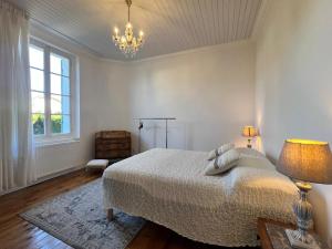 a white bedroom with a bed and a chandelier at villa des roses in Bergerac