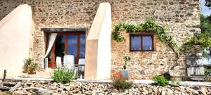a stone house with two windows and a patio at maison infini in Les Salles-Lavauguyon