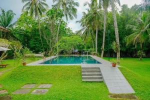 a swimming pool in a yard with palm trees at Muthukirula Resort in Aluthgama
