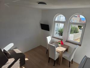 a small living room with a table and two windows at ANTODO Batista in Novalja