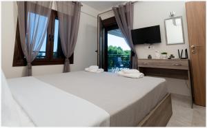 a bedroom with two beds and a tv and a window at Buena Vista - San Mames in Agios Mamas
