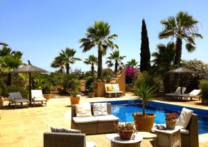a patio with chairs and a pool with palm trees at Finca Alqueria Fosca in Campos