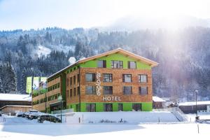 un hôtel dans la neige devant une montagne dans l'établissement Explorer Hotel Kitzbühel, à St. Johann in Tirol