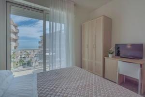 a bedroom with a bed and a television and a balcony at Hotel Constellation in Rimini