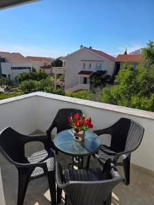 a patio table with chairs and a vase of flowers on a balcony at ANTODO Batista in Novalja