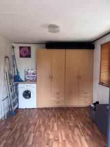 a laundry room with wooden cabinets and a washer and dryer at Chalet Feanzicht in Earnewâld +24 photos