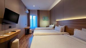 a hotel room with two beds and a flat screen tv at Hotel Bankir Khiva in Khiva