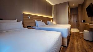 two beds in a hotel room with white sheets at Hotel Bankir Khiva in Khiva