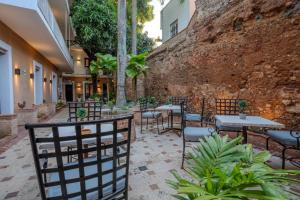 a patio with tables and chairs and a wall at LUCA HOTEL Heritage Residences Signature Collection in Santo Domingo