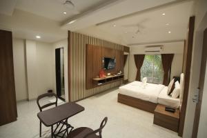 a bedroom with a bed and a desk and a tv at The Grand Leela Resort in Khopoli