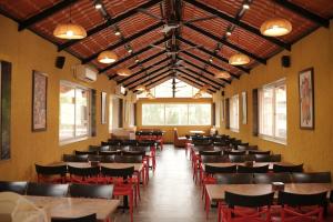 a dining room with tables and chairs and windows at The Grand Leela Resort in Khopoli