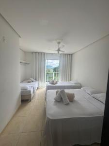 a white room with three beds and a window at Pousada da Esdras in Capitólio