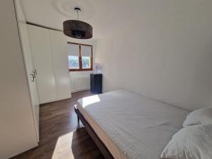 a white bedroom with a bed and a window at Appartement Pila - Faverges in Faverges