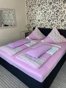 a bed with purple and white pillows on it at Ferienhaus Belkot in Bad Sachsa