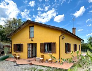 a yellow house with chairs and a patio at La Casa nel Bosco in Arezzo