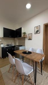 a kitchen with a wooden table and white chairs at Apartman Jakovljević in Gornja Toplica