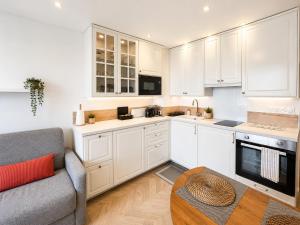 a kitchen with white cabinets and a couch and a table at Méva in Courseulles-sur-Mer