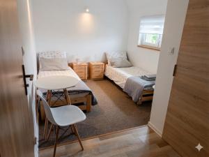 a small room with two beds and a table and chair at Łapacz Mazurskich Chwil in Orzysz