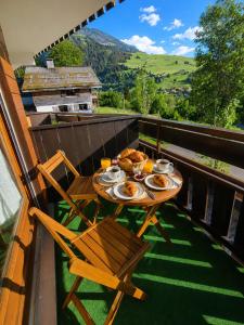 a table and chairs on a balcony with food on it at Studio 3 étoiles Les Helianthes, Wifi, Garage in La Clusaz