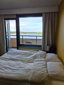 a bed in a room with a large window at Huone upealla järvimaisemalla in Ikaalinen