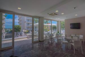 a large room with tables and chairs and windows at Hotel Constellation in Rimini