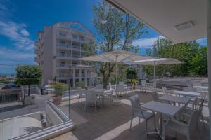 a patio with tables and chairs and umbrellas at Hotel Constellation in Rimini