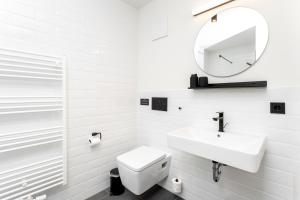 a white bathroom with a sink and a mirror at Global Living Passau Ludwigplatz in Passau +34 photos