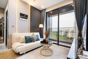 a living room with a white couch and a large window at The Fermin Premium Studios in Ho Chi Minh City