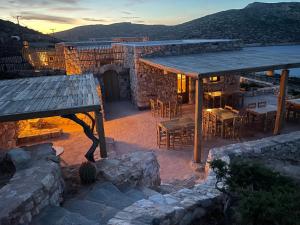 a patio with a table and chairs and a stone building at Phisis Nature Retreat in Donoussa