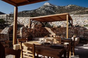 a restaurant with a wooden table and a stone wall at Phisis Nature Retreat in Donoussa +50 photos