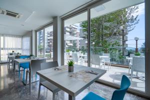 a restaurant with tables and chairs and large windows at Hotel Constellation in Rimini