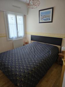 a bedroom with a bed with a black comforter at directe plage à moins de 100m in La Turballe