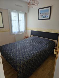 a bedroom with a bed with a blue comforter at directe plage à moins de 100m in La Turballe