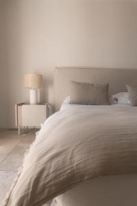 a white bedroom with a large bed with a lamp at Hôtel Pineto in Biguglia +30 photos