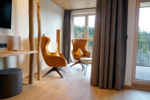 a living room with two chairs and a table and a window at Das Waldhotel - Spa & Wellness Resort in Todtnau