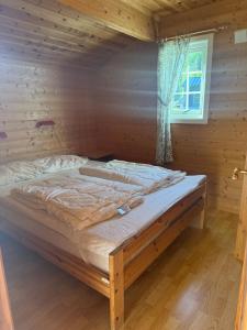 a bed in a wooden room with a window at Hafslo hytteutleige Straumane in Luster