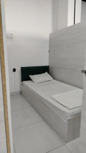 a white bed in a white room with a green headboard at Em capsule Hostel Baku in Baku
