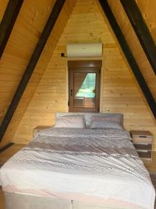 a bed in a wooden room with a window at Viaggio Berane in Berane