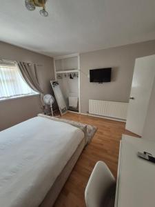 a bedroom with a large white bed and a television at Quiet and professional friendly in Cardiff