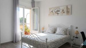 a white bedroom with a bed and a window at Hostel-Élisée-Perpignan in Perpignan