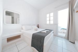 a white bedroom with a bed and a mirror at ALMA THERA Boutique Hotel in Perissa