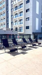 a row of chairs sitting in front of a building at Apartamento completo e elegante no centro de Pouso Alegre in Pouso Alegre