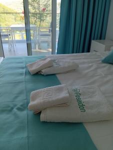 two towels are sitting on a bed with a window at Poseidon Complex in Paleokastritsa